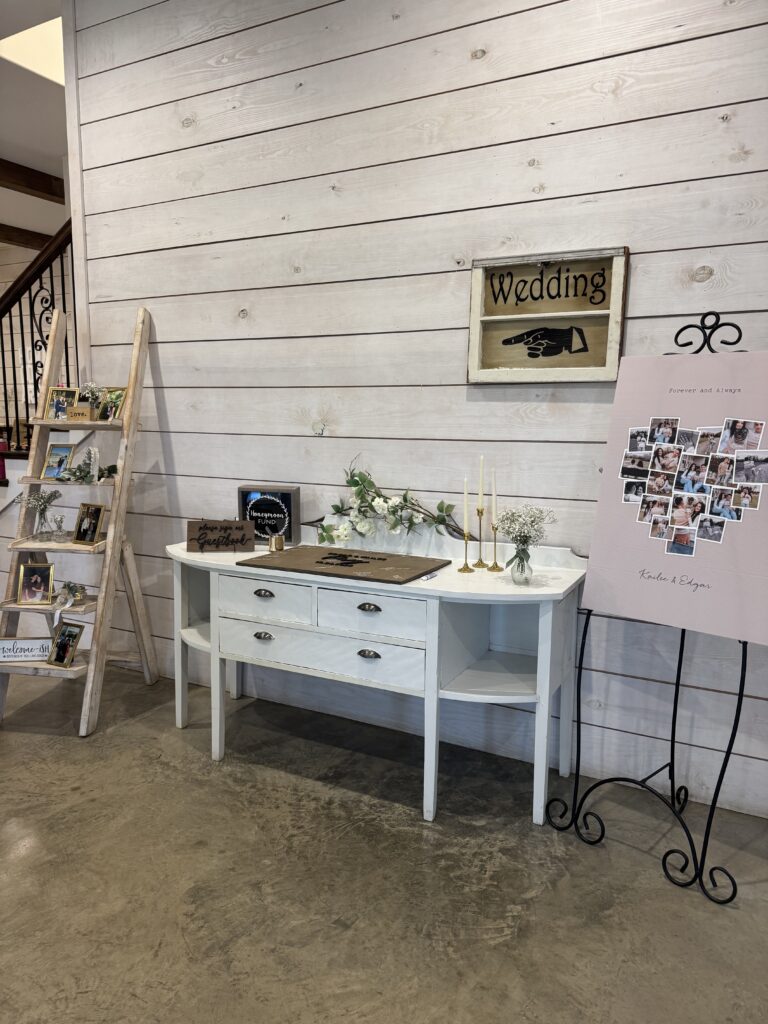 Rustic wedding welcome table setup at The Establishment Barn in Terrell TX with guestbook, candles, and photo display