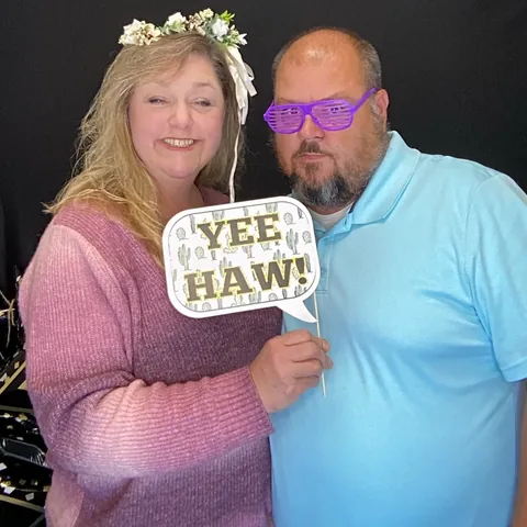 Couple holding a Yee Haw sign at a Greenville photo booth