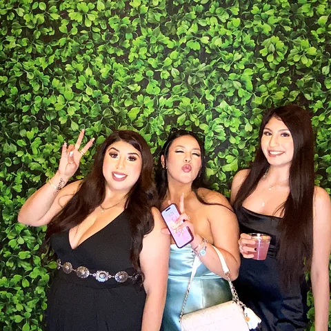 Three friends posing at the Rosy Cheeks photo booth in Terrell