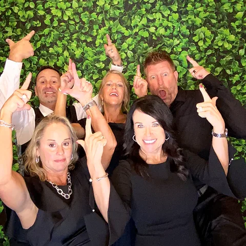 Group of wedding guests pointing at the camera at the photo booth