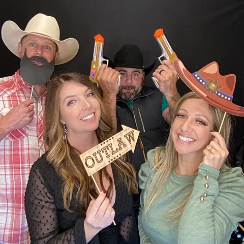 Group of friends with an Outlaw sign and western props at the photo booth