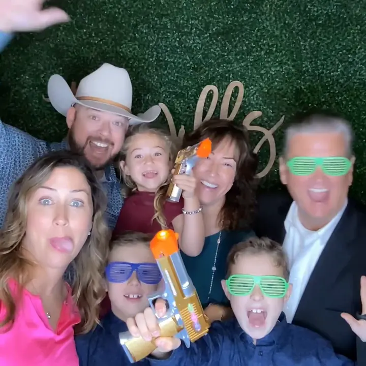 Group of guests posing together in colorful party glasses at the photo booth