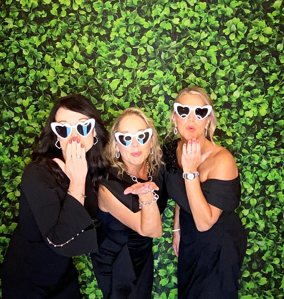 Wedding guests wearing white sunglasses posing at the Rosy Cheeks photo booth in Terrell, Texas