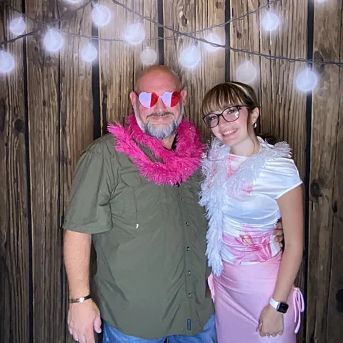 Two guests wearing heart-shaped glasses and a pink boa at the birthday party