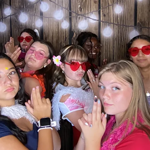 Friends wearing heart-shaped glasses and holding props at London’s Sweet Sixteen