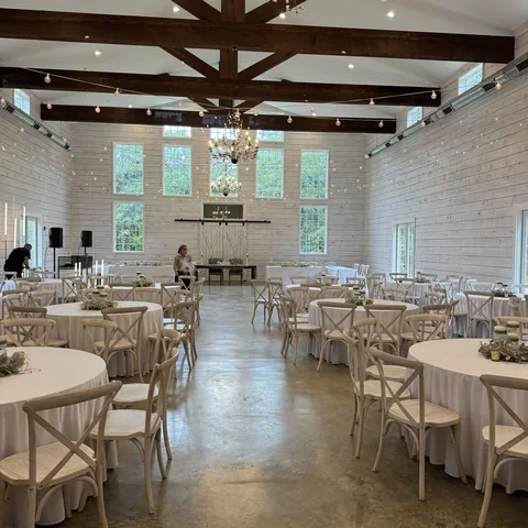 Reception hall with tables set for a wedding at The Establishment Barn in Terrell